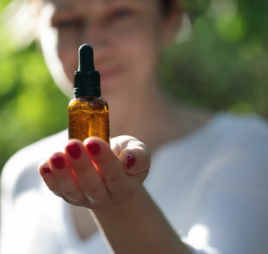Woman using Vesper Mushrooms liquid extract dropper bottle as part of a daily wellness routine